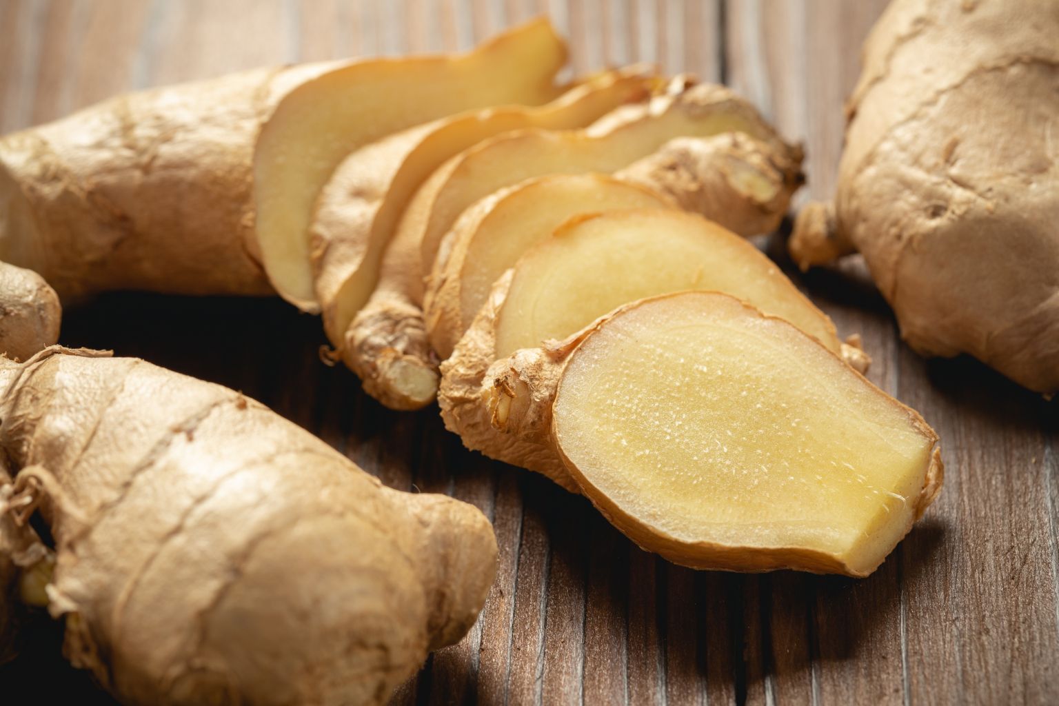 Jengibre fresco rallado y en polvo sobre tabla de madera rústica