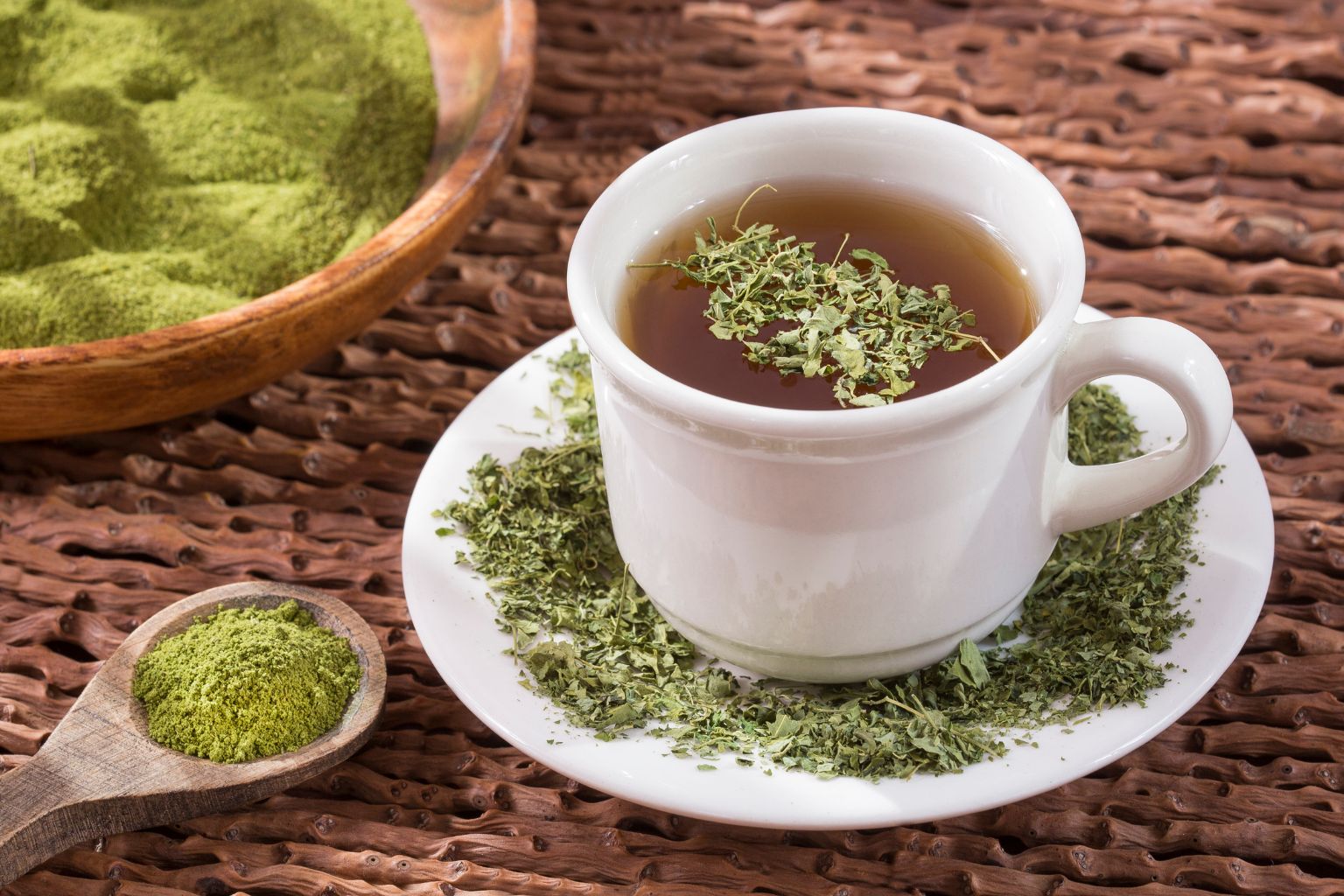 Taza humeante de té de moringa en ambiente relajante con hojas frescas